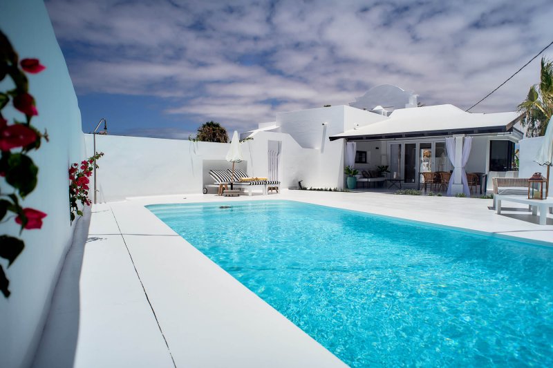 Piscina con hamacas y sombrilla